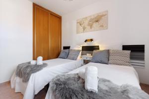 two beds in a room with white and gray at Te Mahana Nei House in Costa Calma