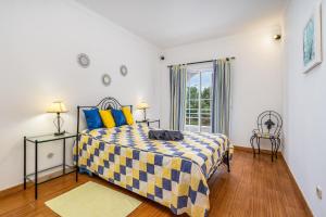 a bedroom with a bed with a yellow and blue checkered blanket at Villa Raposo em Porches in Porches
