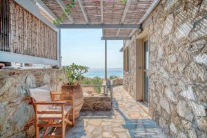 a patio with two chairs and a stone wall at Karavi in Rámos