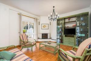 a living room with a couch and chairs and a tv at Villa Raposo em Porches in Porches
