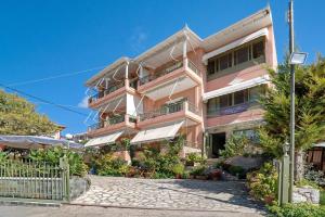 a pink building with balconies on a street at Nontas Home 24 in Kalamitsi