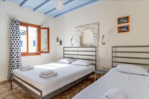 two beds in a room with white walls and a window at En Tino 3 in Tinos