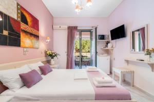 a bedroom with a large white bed with purple pillows at Nontas Home 24 in Kalamitsi