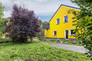 a yellow house with a tree in front of it at Wohnung am Stadtrand im Grünen in Zeuthen
