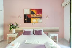 a bedroom with a white bed and a painting on the wall at Nontas Home 24 in Kalamitsi