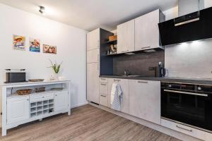 a kitchen with white cabinets and black appliances at Ferienwohnung Schätzle in Schuttertal +16 photos