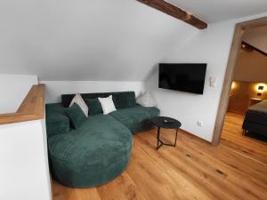 ein Wohnzimmer mit einer grünen Couch und einem Flachbildfernseher in der Unterkunft Hümmer Chalets in Breitengüßbach