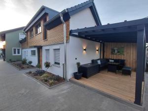 ein Haus mit Holzterrasse und schwarzer Pergola in der Unterkunft Hümmer Chalets in Breitengüßbach