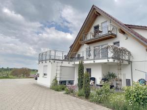 a white house with a balcony and a driveway at Biohof Stotz in Friedrichshafen