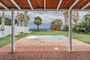 an outdoor patio with a pool and palm trees at Villa Cassis in Adeje