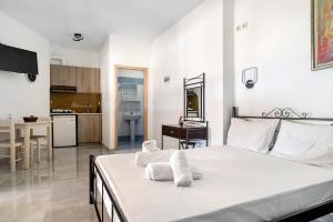 a bedroom with a white bed and a kitchen at Iguana studio 12 in Preveza