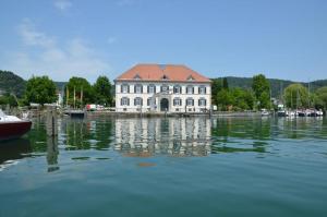 a large white building with a red roof on the water at Haus Zum Haiden in Bodman-Ludwigshafen