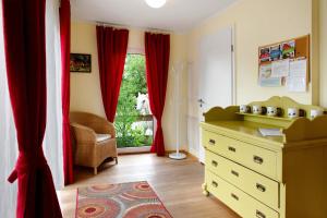 a room with a dresser and a window with red curtains at Landhüsli Illmensee in Illmensee