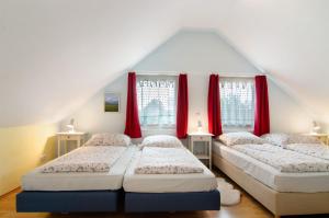 three beds in a room with red curtains at Landhüsli Illmensee in Illmensee
