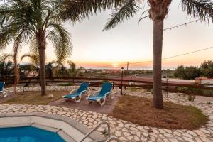 a pool with two chairs and a palm tree at Villa Ina in Cinisi