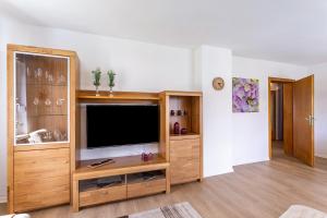 a living room with a flat screen tv in a wooden entertainment center at Annes Stübchen in Schmallenberg