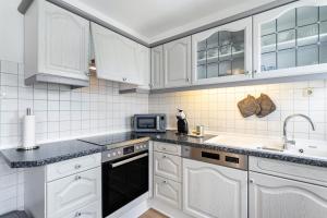 a kitchen with white cabinets and a sink and a microwave at Annes Stübchen in Schmallenberg +19 photos