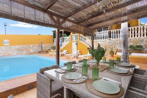 a table with chairs next to a swimming pool at Villa Christisay in San Bartolomé
