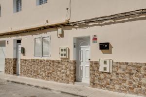 a white building with a door and a stone wall at 1b Srv in Vecindario