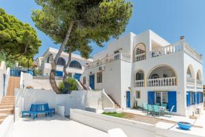 a white house with blue chairs in front of it at Wavedance Accommodation in Salamina