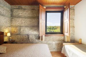 a bedroom with a window in a stone wall at Casa de Andrães Magnolias in Marco de Canaveses +21 photos