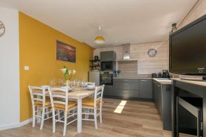 a kitchen with a table with chairs and a television at Gîte Le Champ Du Bois in Missillac +21 photos