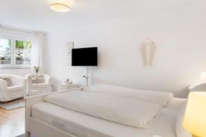 a white bedroom with a bed and a flat screen tv at Privatzimmer Kippenhausen in Immenstaad am Bodensee +16 photos