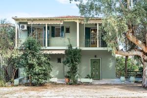 a house with a green door and a tree at Old Boat apartment in Nikiana