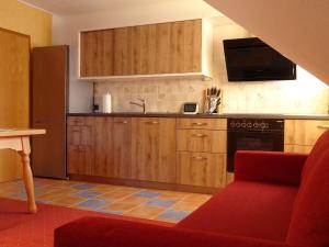 a kitchen with wooden cabinets and a red couch at Ferienwohnung Mühlengrün in Oberwolfach