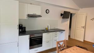 a kitchen with white cabinets and a stove top oven at Pfoten und Berge Oberreute in Oberreute +29 photos