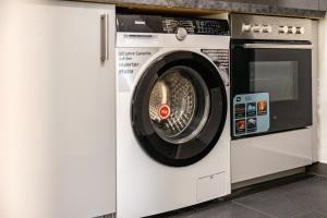 a washing machine in a kitchen with a microwave at Aldars Urban Trio Suite Nr. 9 in Munich