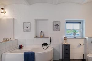 a white bathroom with a tub and a window at Hof Musial in Pokrent +34 photos