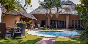 a resort with a swimming pool with chairs and a table at Green Oasis Lodges in Harare
