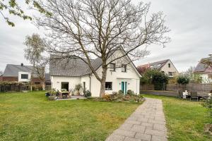 a white house with a tree in the yard at Ferienwohnung Feuerbach in Telgte