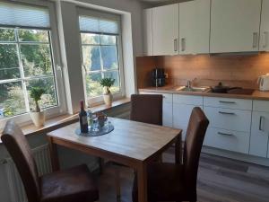 a kitchen with a wooden table and chairs and windows at Ferienwohnung Zur Basemicke in Schmallenberg