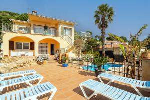a villa with a swimming pool and two lounge chairs at Disfruta De La Costa Brava in Lloret de Mar