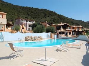 a swimming pool in a resort with two chairs at L'Angolo di Noemi - Chia in Chia