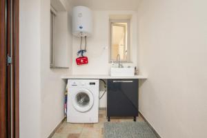 a laundry room with a washing machine and a sink at L'Angolo di Noemi - Chia in Chia +23 photos