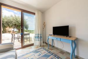 a living room with a tv and a table with a television at L'Angolo di Noemi - Chia in Chia