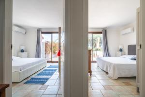 a bedroom with two beds and a hallway with two windows at L'Angolo di Noemi - Chia in Chia