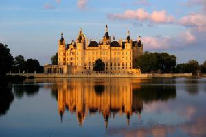 a large building with its reflection in the water at Hausboot Saturn in Schwerin