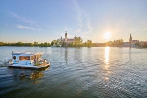 a boat on a river with a city in the background at Hausboot Saturn in Schwerin +5 photos
