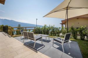 a patio with a table and chairs and an umbrella at Casa Panoramica in Tignale