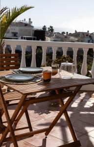 a wooden table with plates and bowls on a balcony at Rd02 La Casa Hermosa in Torrox