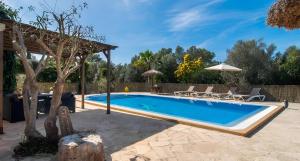 a pool in a backyard with chairs and an umbrella at Sa Costa in Campos