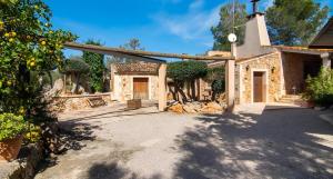 an entrance to a stone house with trees and a building at Sa Costa in Campos