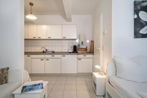 a small kitchen with white cabinets and a couch at Fewo Eg Rechts - Hunde erlaubt in Oberteuringen