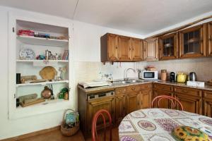 a kitchen with wooden cabinets and a table and a sink at Orizzonte Calmo in Borghetto Di Borbera +19 photos
