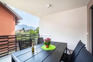 a dining table with a bottle of wine and flowers on a balcony at Jj City Apartment in Lagundo
