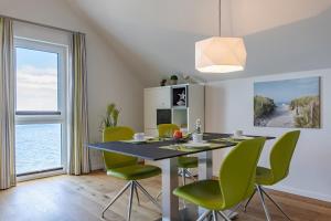 a dining room with a table and green chairs at Reeders Topp by Seeblick Ferien in Olpenitz